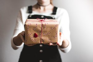 Eine Person hält ein Geschenk in der Hand, es sieht weihnachtlich aus. 