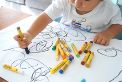 Kleinkind zeichnet mit Wachsmalkreiden
